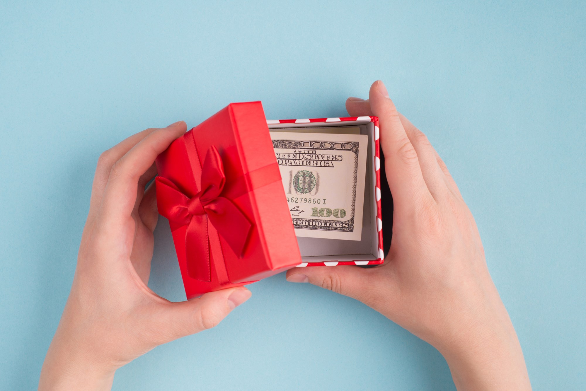 Top above overhead close up first person view photo of female hands open box with 100 american banknote isolated over paste blue color background