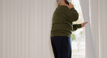 Elderly man on phone and looking out of window
