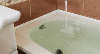 Strong stream of water pours into the tub. Water pours out. Tub overflows. Close up