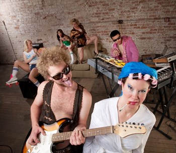 Young guitarist teasing woman in curlers at a 1970s Disco Music Party