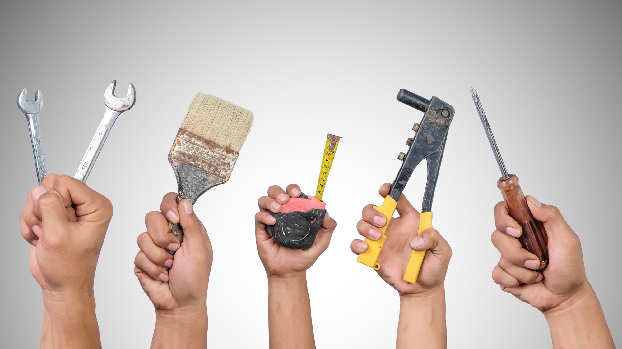 Hands holding different carpentry tools isolated on white background.